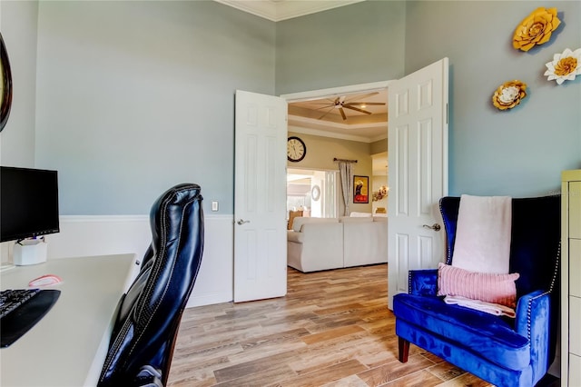 home office with a ceiling fan, a tray ceiling, crown molding, and wood finished floors