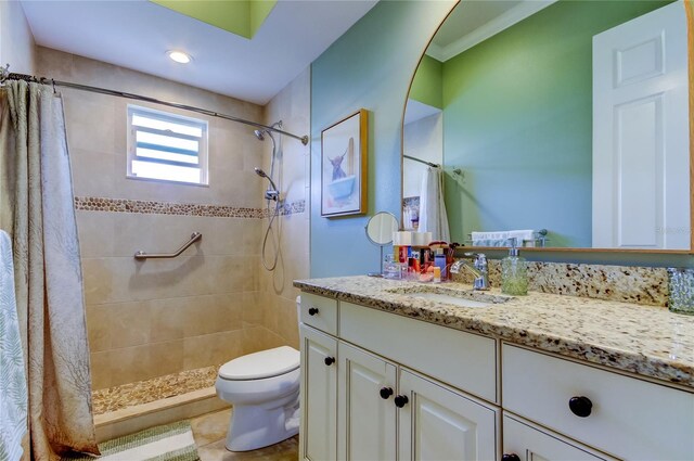 bathroom featuring toilet, tiled shower, and vanity