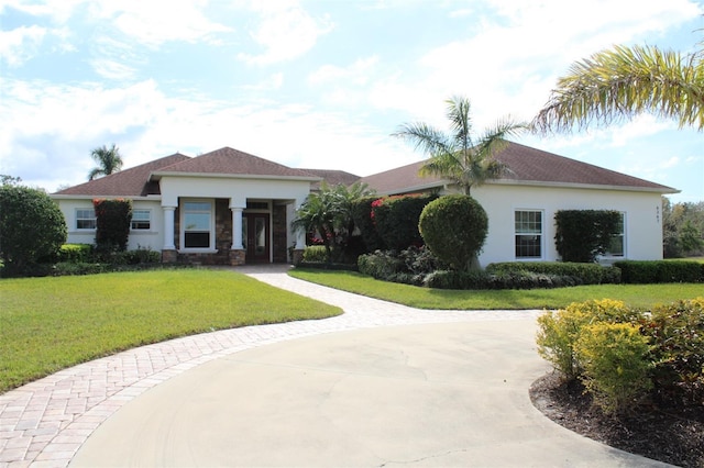 view of front facade with driveway, a front yard, and stucco siding