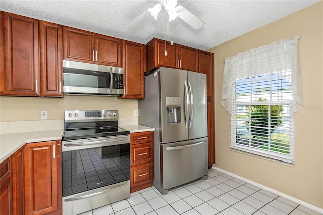 kitchen with light tile patterned flooring, ceiling fan, stainless steel appliances, and a textured ceiling