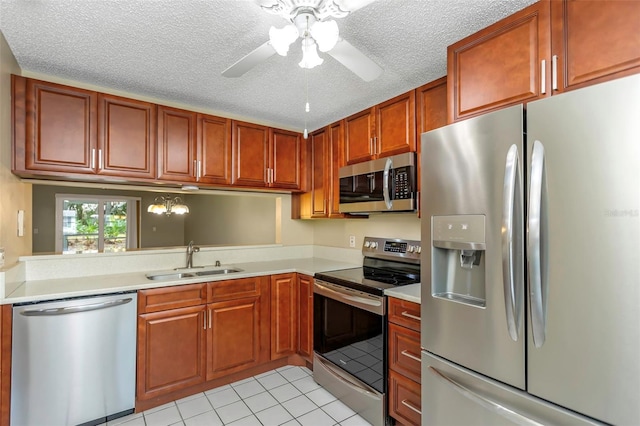 kitchen with appliances with stainless steel finishes, sink, light tile patterned floors, and a textured ceiling