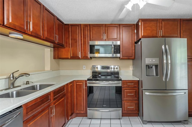 kitchen featuring appliances with stainless steel finishes, sink, light tile patterned floors, ceiling fan, and a textured ceiling