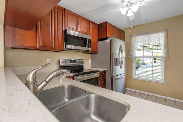 kitchen with stainless steel appliances, sink, a textured ceiling, and light tile patterned floors