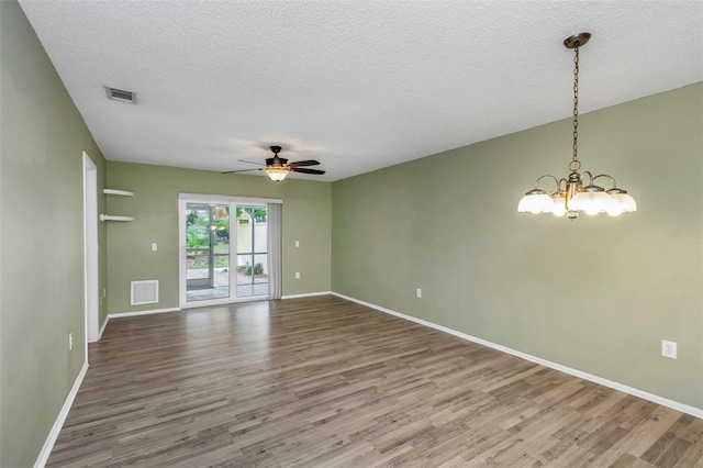 empty room with wood-type flooring, ceiling fan with notable chandelier, and a textured ceiling