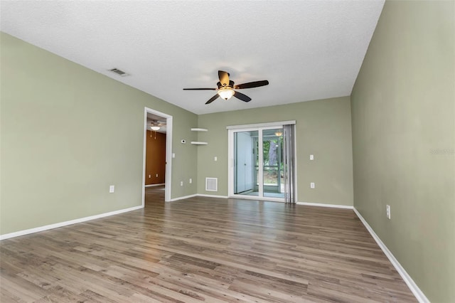 empty room with ceiling fan, a textured ceiling, and light wood-type flooring