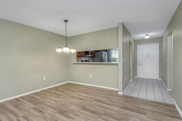 interior space featuring a textured ceiling, a notable chandelier, and light hardwood / wood-style floors