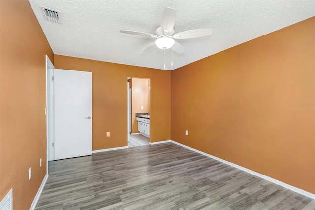 unfurnished bedroom featuring ceiling fan, ensuite bath, light hardwood / wood-style floors, and a textured ceiling