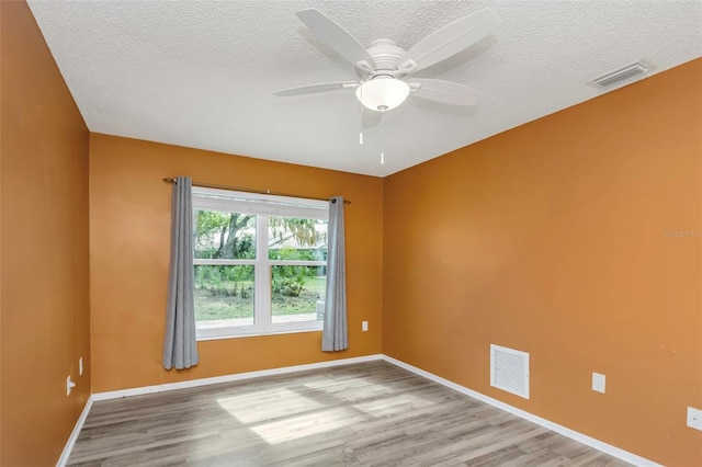 empty room featuring ceiling fan, a textured ceiling, and light hardwood / wood-style floors