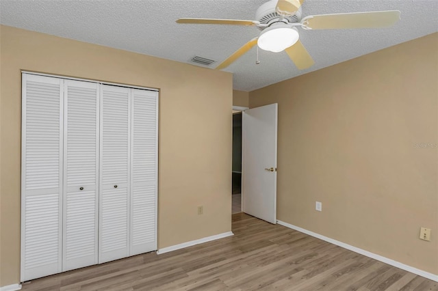 unfurnished bedroom with ceiling fan, light hardwood / wood-style floors, a closet, and a textured ceiling