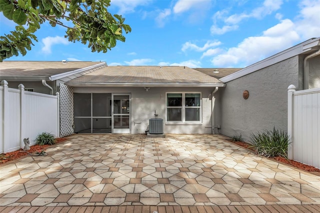 back of property with a sunroom, central AC unit, and a patio