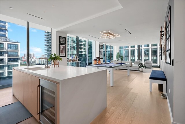 1000 Water St Unit 1002, Tampa, FL 33602 - kitchen with sink, a wall of windows, light hardwood / wood-style floors, a center island with sink, and beverage cooler
