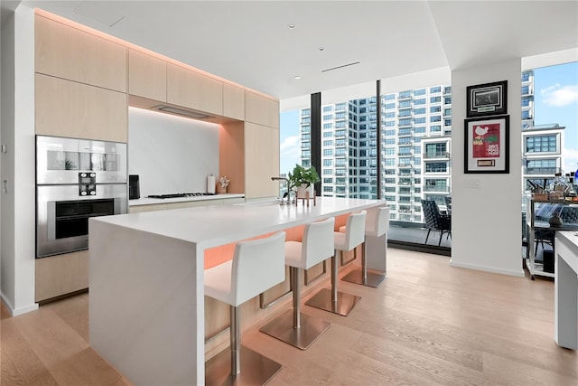 1000 Water St Unit 1002, Tampa, FL 33602 - kitchen with a breakfast bar, sink, light hardwood / wood-style floors, floor to ceiling windows, and a center island with sink