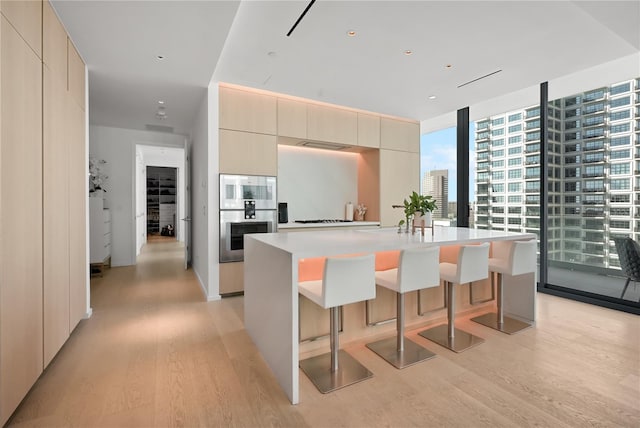 1000 Water St Unit 1002, Tampa, FL 33602 - kitchen with a wall of windows, a breakfast bar, a kitchen island with sink, and light hardwood / wood-style flooring