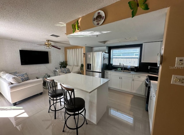 kitchen with a kitchen bar, sink, a kitchen island, stainless steel appliances, and white cabinets