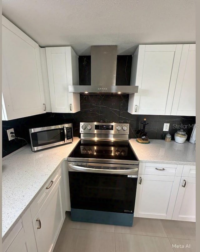 kitchen with backsplash, appliances with stainless steel finishes, wall chimney exhaust hood, and white cabinets