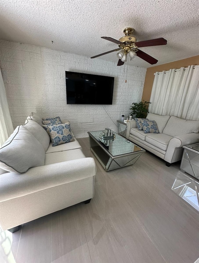 living room featuring hardwood / wood-style flooring, ceiling fan, and a textured ceiling