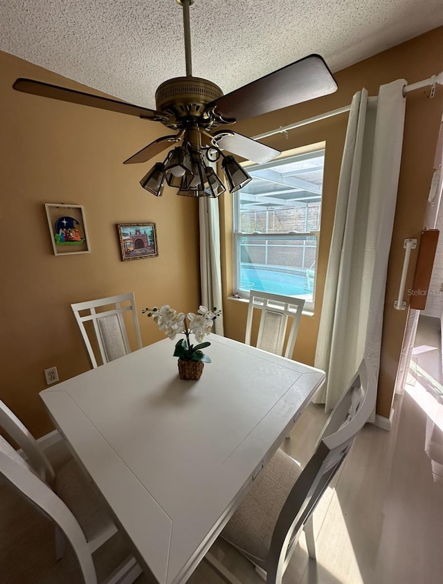 dining room with a textured ceiling, wood-type flooring, and ceiling fan