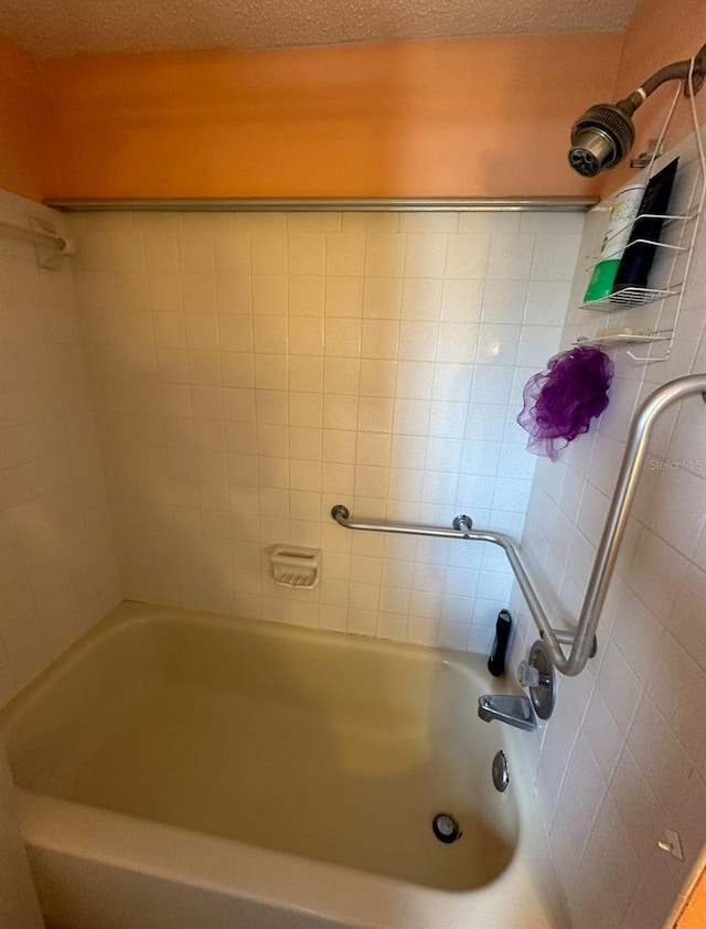 bathroom featuring tiled shower / bath combo and a textured ceiling