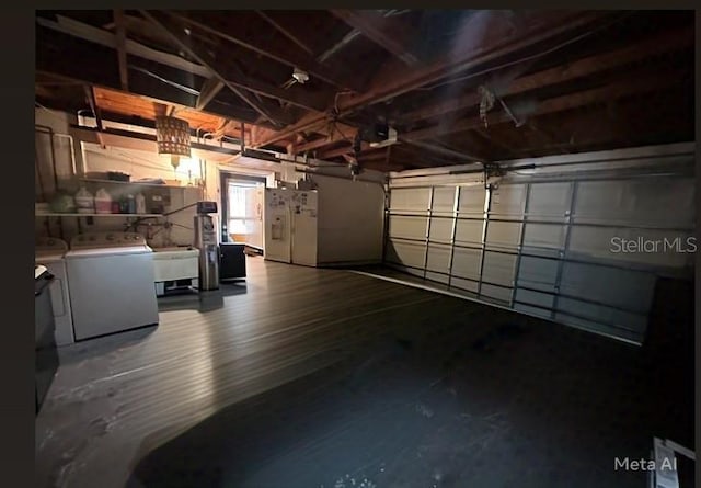 garage featuring washing machine and dryer and white fridge with ice dispenser