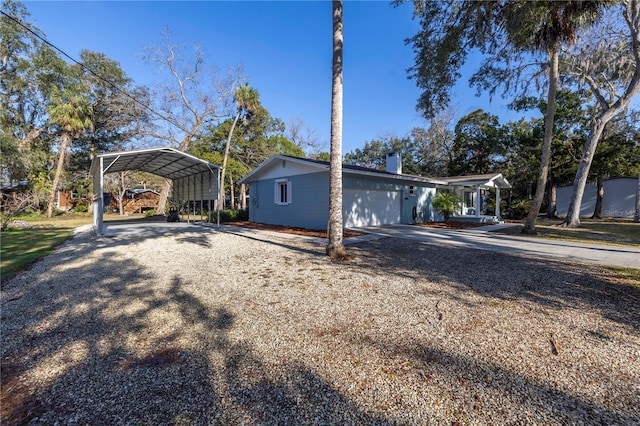 view of front of house with a carport, gravel driveway, and a chimney