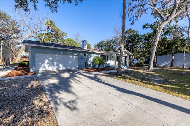 single story home featuring a garage, a front yard, concrete driveway, and a chimney