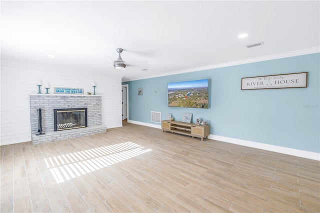 unfurnished living room with a fireplace, crown molding, visible vents, and wood finished floors