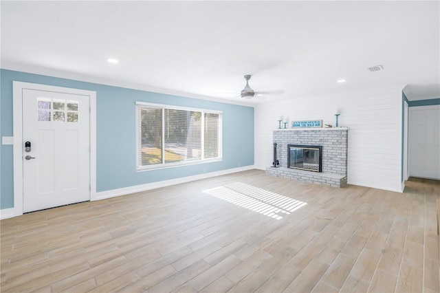 unfurnished living room with visible vents, baseboards, a ceiling fan, a brick fireplace, and light wood finished floors