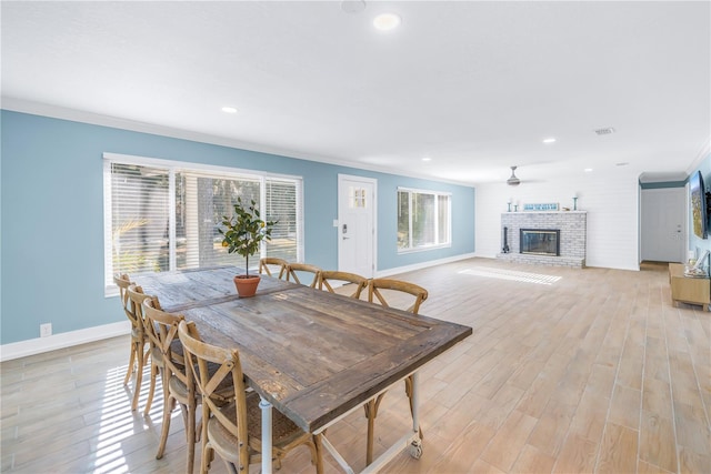 dining space with ornamental molding, a fireplace, visible vents, and light wood-style floors