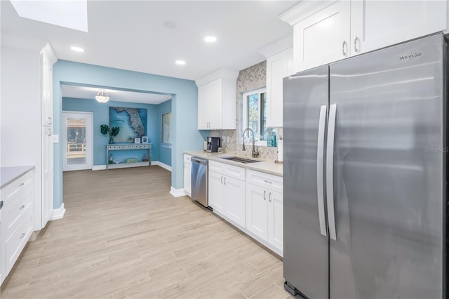 kitchen featuring a sink, stainless steel appliances, light countertops, white cabinetry, and backsplash