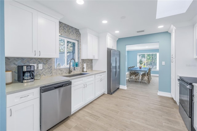 kitchen with stainless steel appliances, a sink, light countertops, and white cabinets