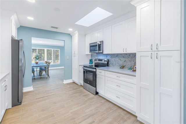 kitchen featuring light countertops, appliances with stainless steel finishes, backsplash, and visible vents