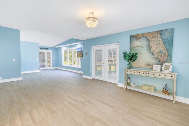 unfurnished living room with french doors, vaulted ceiling, baseboards, and wood finished floors