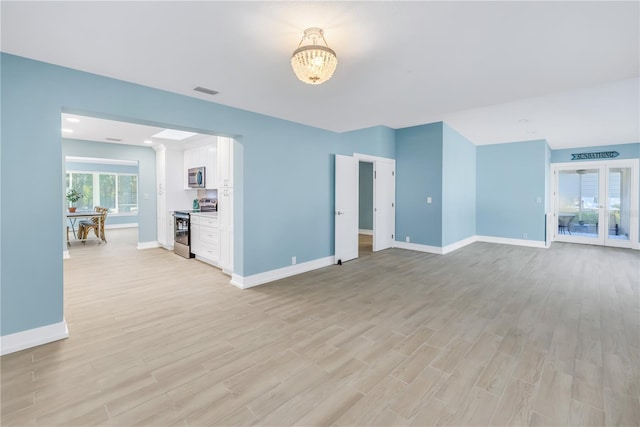 unfurnished living room featuring light wood-style floors, visible vents, and baseboards