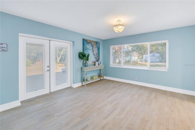 unfurnished room featuring french doors, baseboards, and light wood finished floors