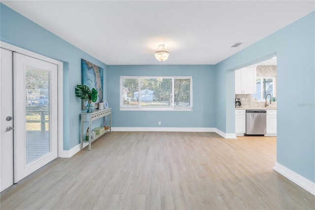 interior space featuring a healthy amount of sunlight, light wood-type flooring, visible vents, and baseboards