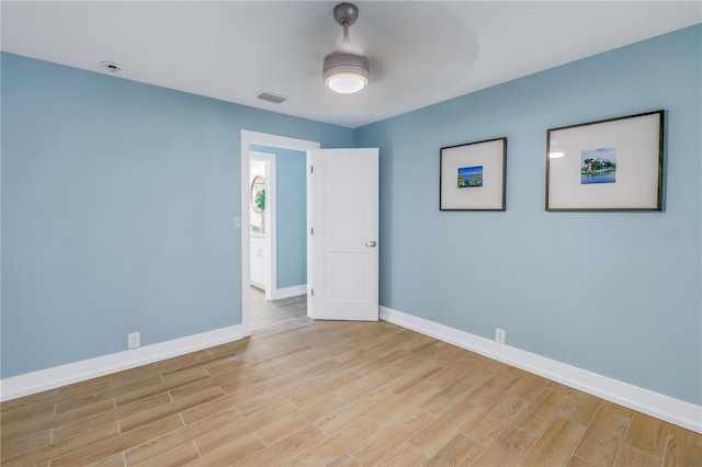 unfurnished room featuring light wood-style floors, visible vents, baseboards, and a ceiling fan