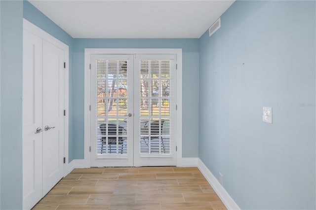 doorway featuring wood tiled floor, visible vents, baseboards, and french doors