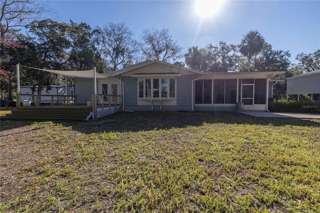 back of property with a sunroom, a lawn, a deck, and french doors