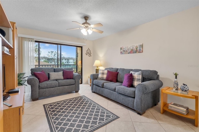 living room with light tile patterned floors, ceiling fan, and a textured ceiling