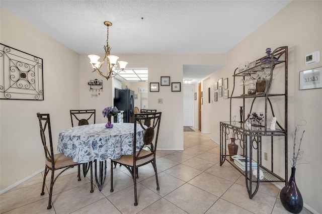 dining space with a chandelier, light tile patterned flooring, and baseboards