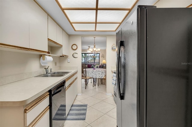 kitchen featuring black appliances, a sink, light countertops, a chandelier, and light tile patterned floors