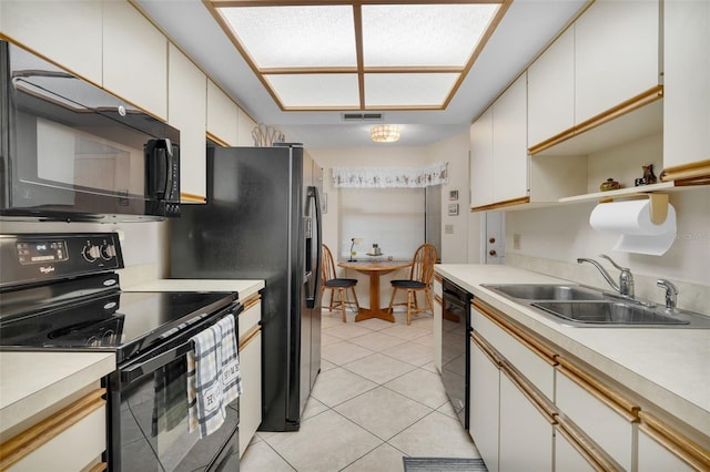 kitchen with black appliances, a sink, light tile patterned flooring, and light countertops