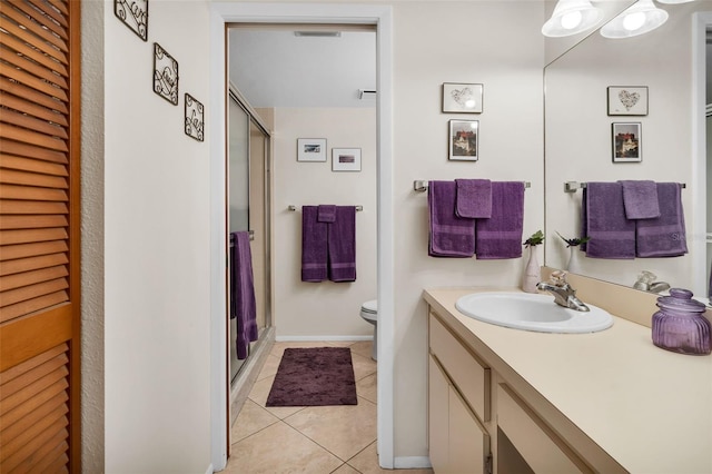 bathroom featuring tile patterned flooring, a shower stall, vanity, toilet, and baseboards