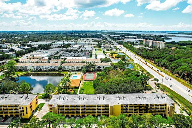 drone / aerial view of a main thoroughfare, a large body of water, and apartment complex / building