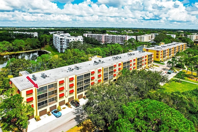 aerial view of apartment complex, a tree filled landscape, and a large body of water