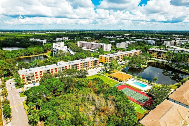 bird's eye view of a nearby body of water, apartment complex / building, and a tree filled landscape
