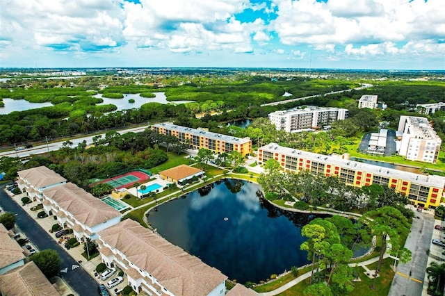 bird's eye view of a large body of water, apartment complex / building, and a tree filled landscape