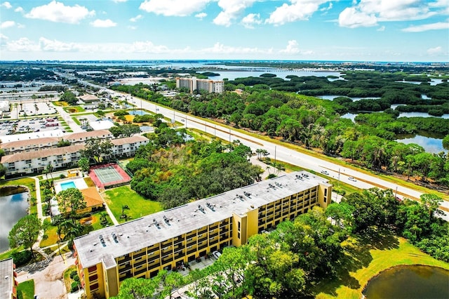drone / aerial view of a nearby body of water and a tree filled landscape