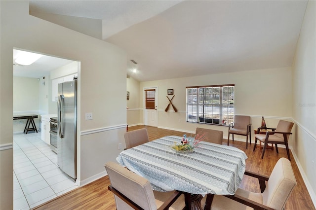 dining area featuring lofted ceiling and light hardwood / wood-style flooring