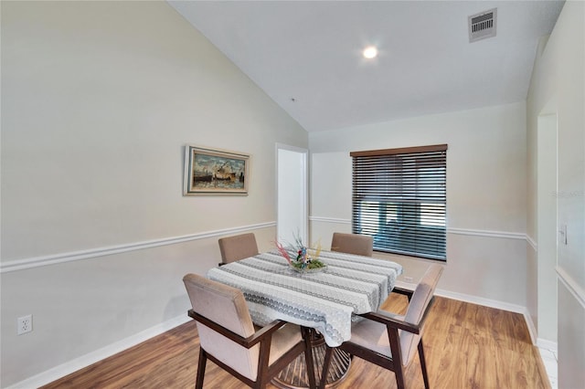 dining space with vaulted ceiling and light wood-type flooring